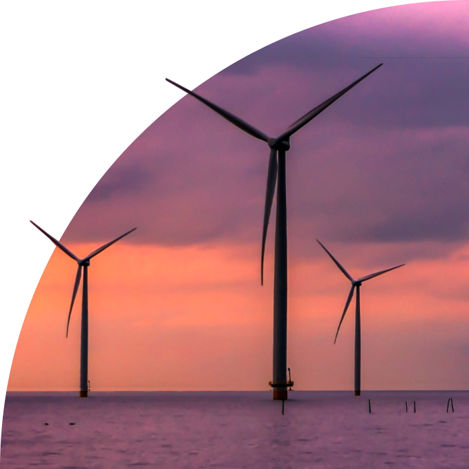 Three offshore wind turbines in the sea at sunset with purple and orange sky